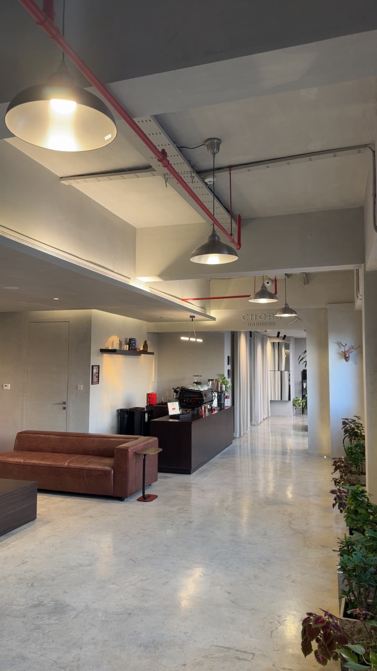 The Chops Barbers lounge with leather seating, coffee bar, and concrete interior